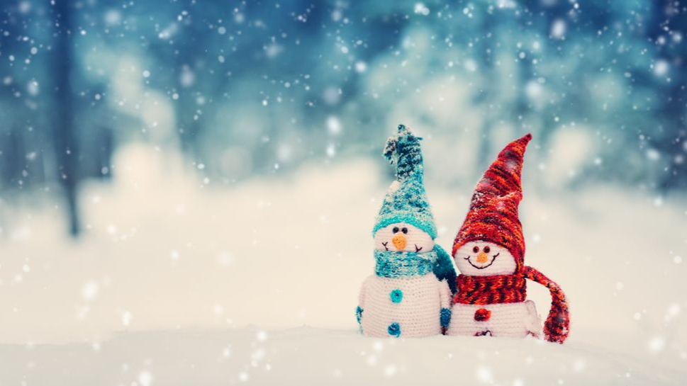 Snowy forest scene with two snowmen dressed in warm holiday hats and scarves.